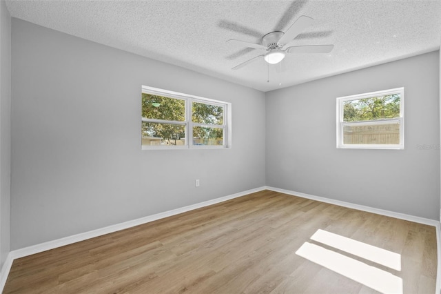 spare room with ceiling fan, a textured ceiling, and light wood-type flooring