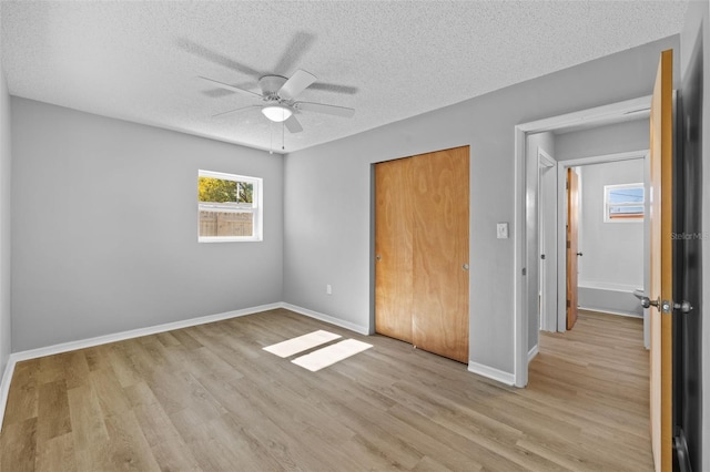 unfurnished bedroom featuring ceiling fan, light hardwood / wood-style floors, a textured ceiling, and a closet