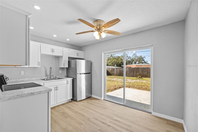 kitchen with stainless steel refrigerator, sink, white cabinets, and stove