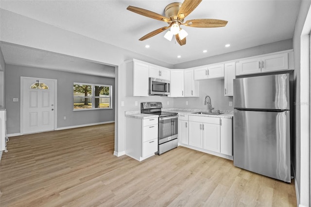 kitchen featuring white cabinetry, sink, ceiling fan, light hardwood / wood-style flooring, and appliances with stainless steel finishes