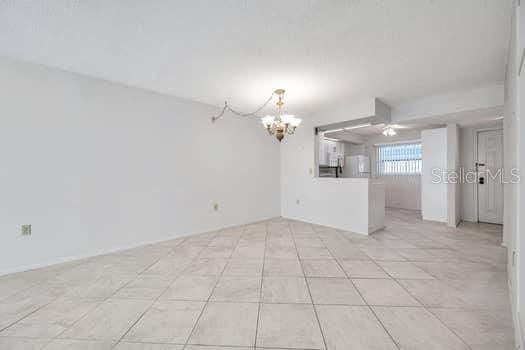 spare room featuring ceiling fan with notable chandelier