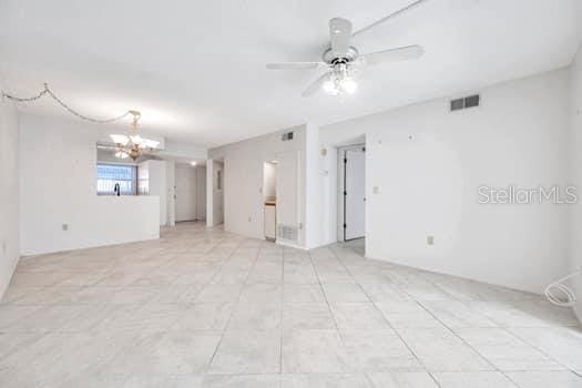 unfurnished room featuring ceiling fan with notable chandelier