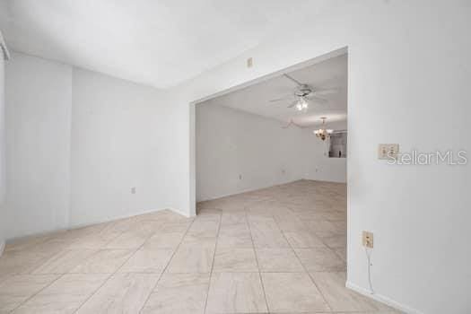 spare room with ceiling fan with notable chandelier