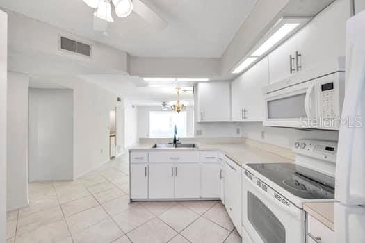 kitchen with white cabinets, white appliances, light tile patterned flooring, and sink