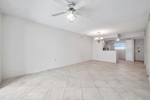 unfurnished room featuring ceiling fan with notable chandelier and light tile patterned floors