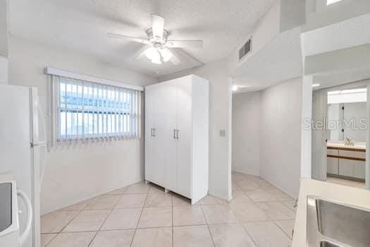 interior space featuring white refrigerator, sink, light tile patterned floors, and ceiling fan