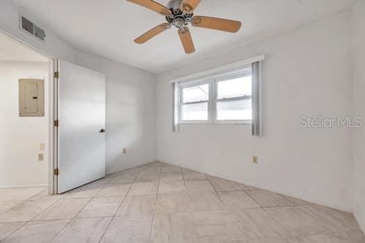 empty room featuring light tile patterned floors, electric panel, and ceiling fan