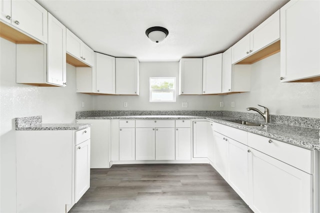 kitchen featuring light stone countertops, sink, and white cabinets