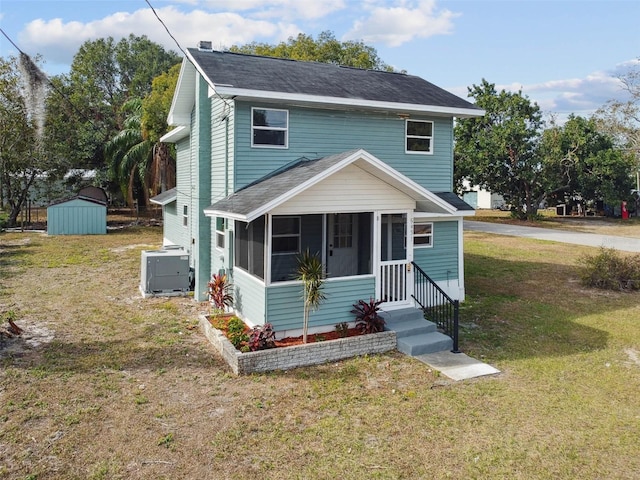 view of property featuring a sunroom, cooling unit, a shed, and a front yard