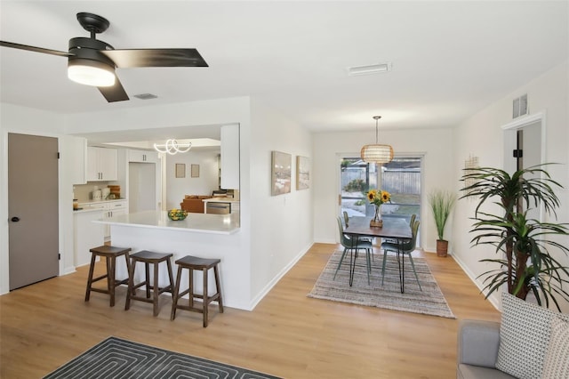 interior space with white cabinets, a kitchen bar, light hardwood / wood-style floors, and ceiling fan