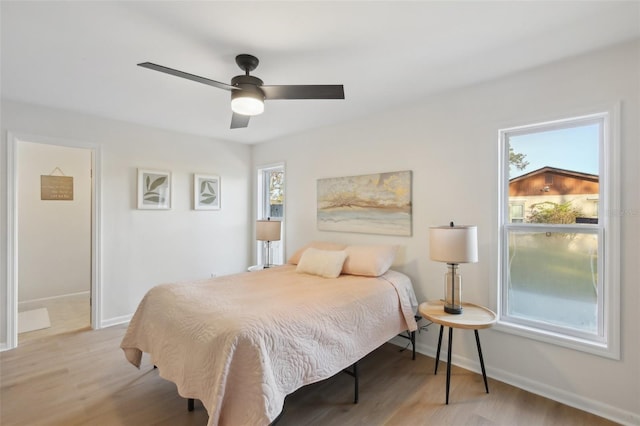 bedroom featuring multiple windows, light hardwood / wood-style floors, and ceiling fan