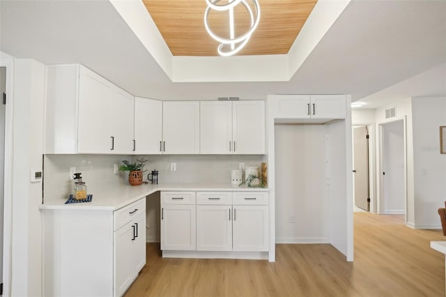 kitchen featuring a raised ceiling, tasteful backsplash, light hardwood / wood-style flooring, white cabinets, and wood ceiling