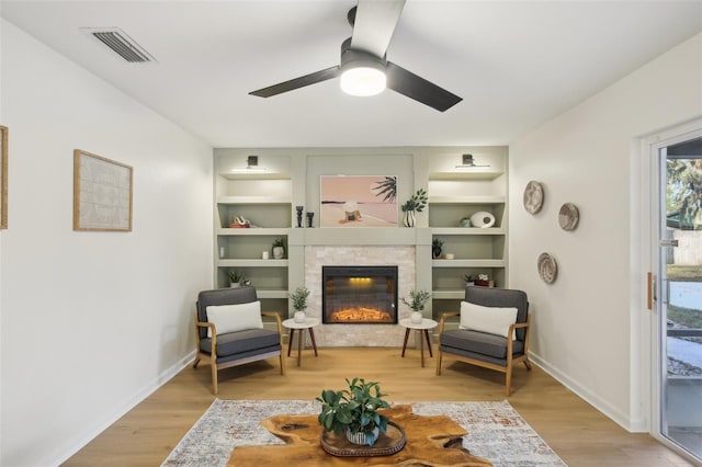 sitting room featuring light hardwood / wood-style floors, built in features, and ceiling fan