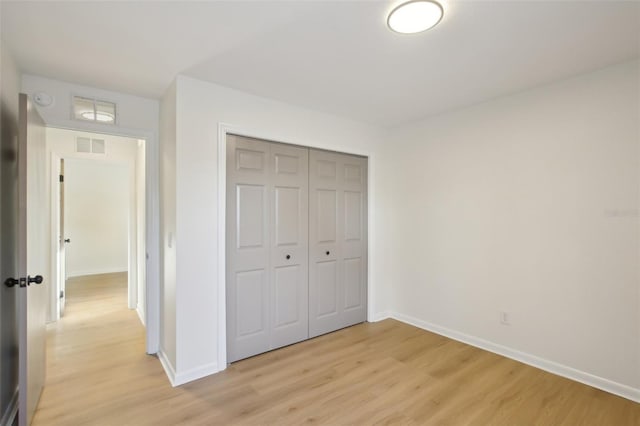 unfurnished bedroom with light hardwood / wood-style flooring and a closet