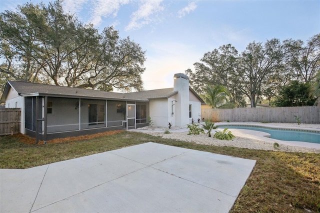 back of house featuring a fenced in pool, a sunroom, and a patio