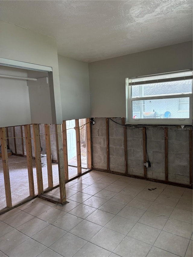 unfurnished room with light tile patterned flooring and a textured ceiling