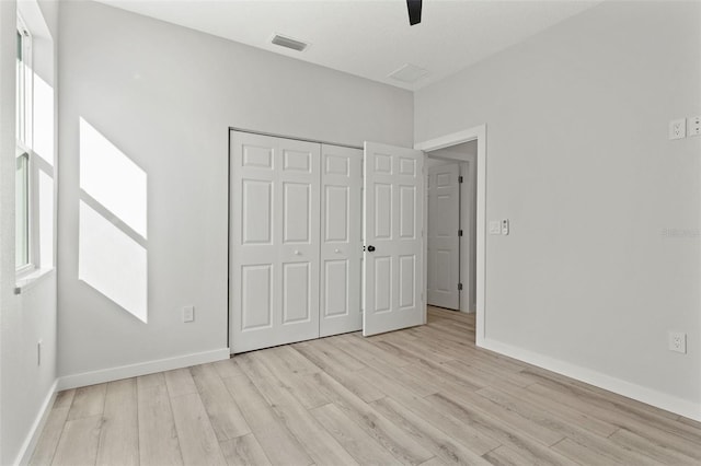 unfurnished bedroom featuring multiple windows, light hardwood / wood-style flooring, a closet, and ceiling fan