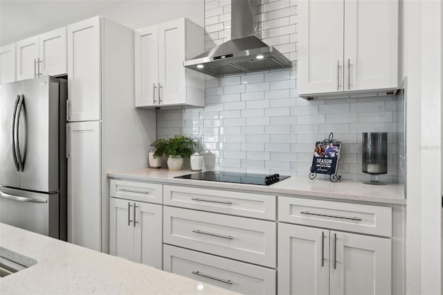 kitchen featuring white cabinets, stainless steel fridge, backsplash, and wall chimney exhaust hood