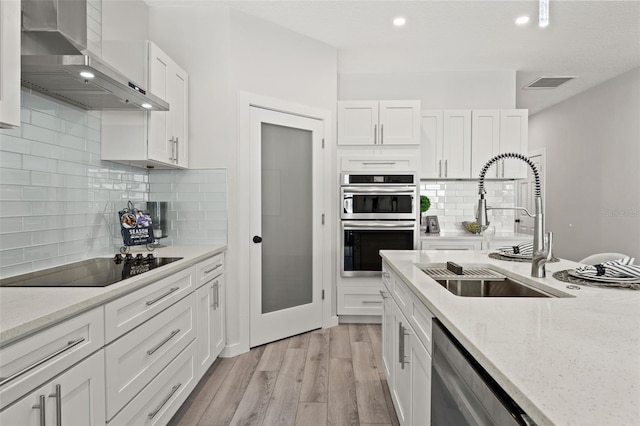 kitchen with sink, white cabinetry, appliances with stainless steel finishes, wall chimney range hood, and backsplash