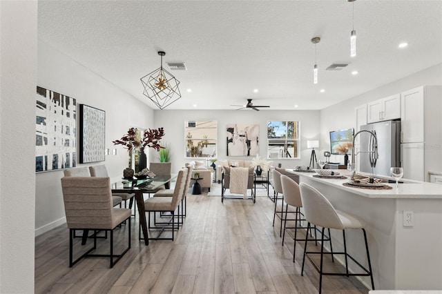 dining room featuring a textured ceiling, ceiling fan, and light hardwood / wood-style flooring