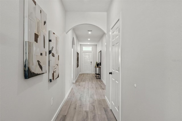 corridor featuring a towering ceiling and light hardwood / wood-style flooring