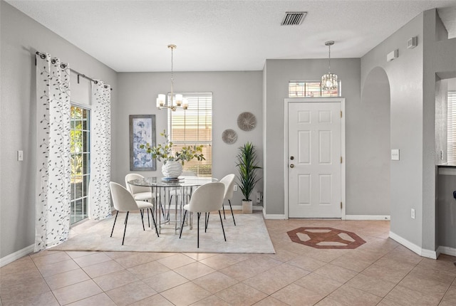 tiled dining area with a chandelier and a textured ceiling