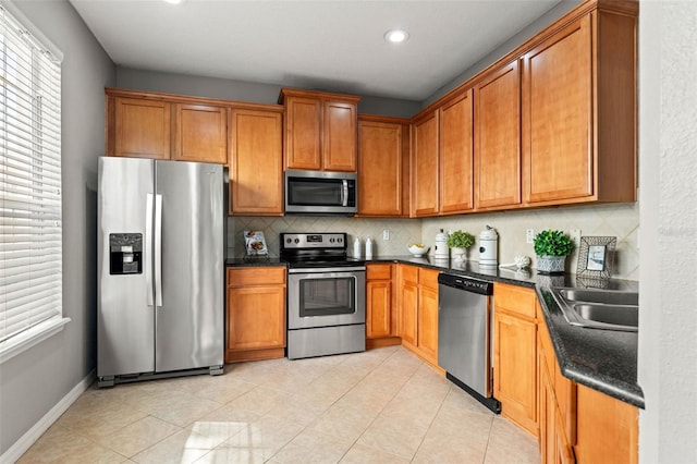 kitchen with backsplash, sink, light tile patterned flooring, and stainless steel appliances