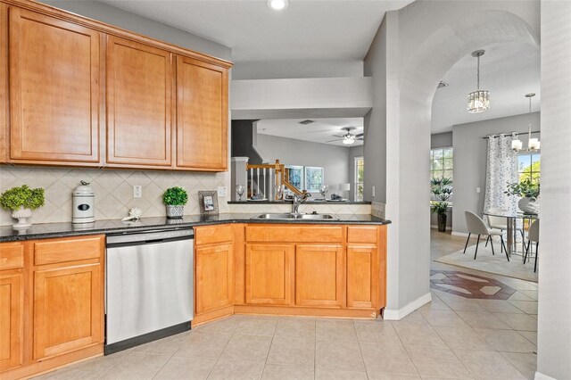 kitchen featuring sink, stainless steel dishwasher, decorative backsplash, light tile patterned floors, and ceiling fan with notable chandelier