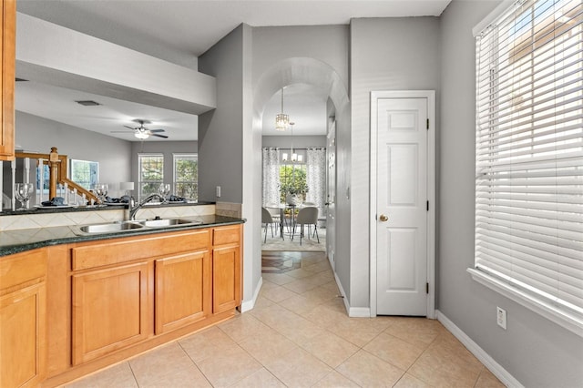 kitchen with light tile patterned floors, ceiling fan with notable chandelier, hanging light fixtures, and sink