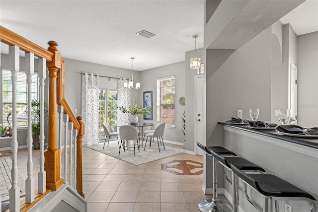 kitchen featuring light tile patterned floors, a textured ceiling, an inviting chandelier, and hanging light fixtures