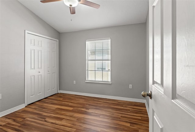 unfurnished bedroom with ceiling fan, a closet, dark hardwood / wood-style flooring, and vaulted ceiling