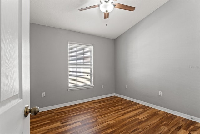 spare room with dark hardwood / wood-style flooring, vaulted ceiling, and ceiling fan