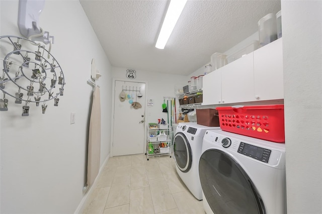 clothes washing area with washer and dryer, cabinets, and a textured ceiling