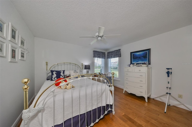 bedroom with ceiling fan, a textured ceiling, and hardwood / wood-style flooring