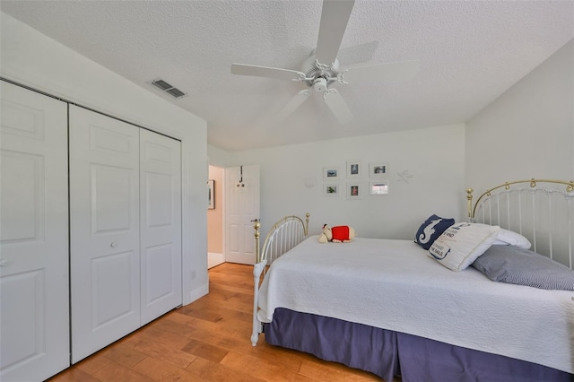 bedroom with ceiling fan, a closet, a textured ceiling, and light hardwood / wood-style flooring