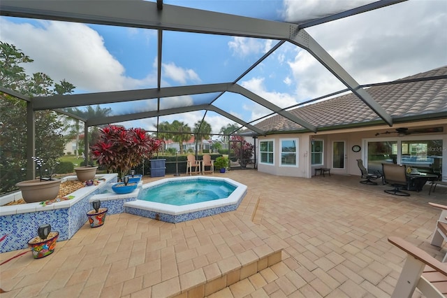 view of pool with a patio area, glass enclosure, and an in ground hot tub