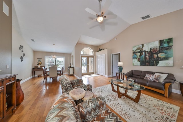 living room with ceiling fan with notable chandelier, lofted ceiling, light hardwood / wood-style floors, and french doors