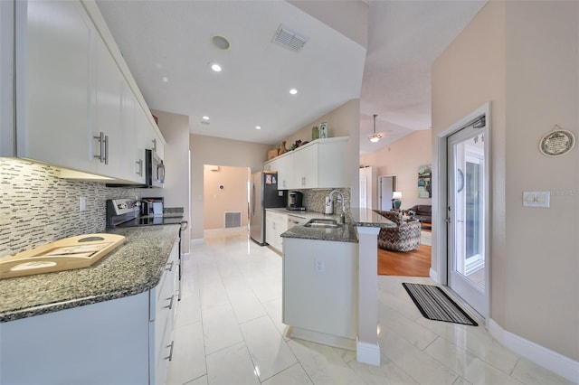 kitchen featuring dark stone countertops, kitchen peninsula, sink, white cabinetry, and stainless steel appliances