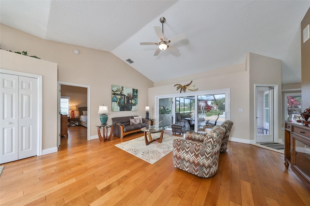 living room featuring ceiling fan, a textured ceiling, light hardwood / wood-style flooring, and lofted ceiling