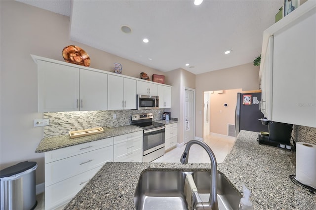 kitchen with white cabinets, appliances with stainless steel finishes, sink, and dark stone counters