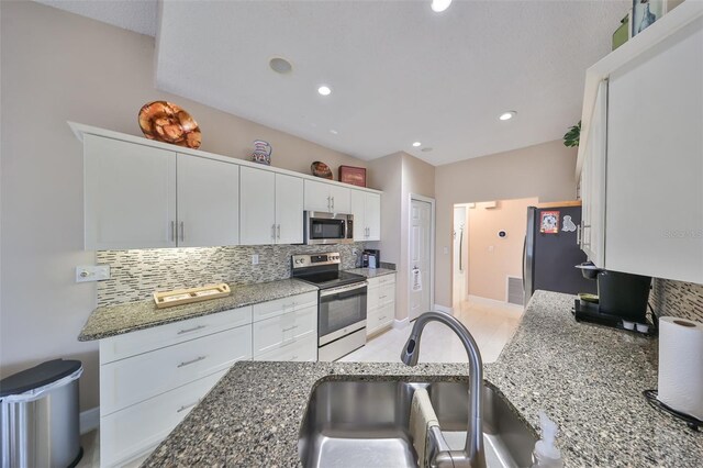 2337 Platinum Dr, Sun City Center, FL 33573 - kitchen featuring backsplash, appliances with stainless steel finishes, a sink, stone countertops, and white cabinetry