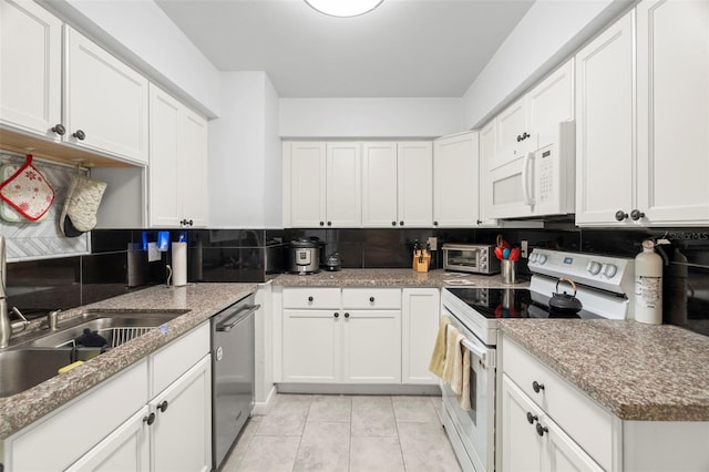 kitchen featuring white appliances, white cabinets, tasteful backsplash, light tile patterned flooring, and light stone counters