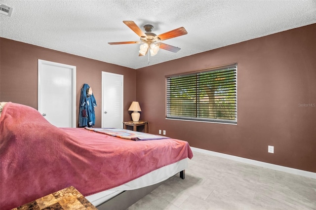 bedroom with ceiling fan and a textured ceiling