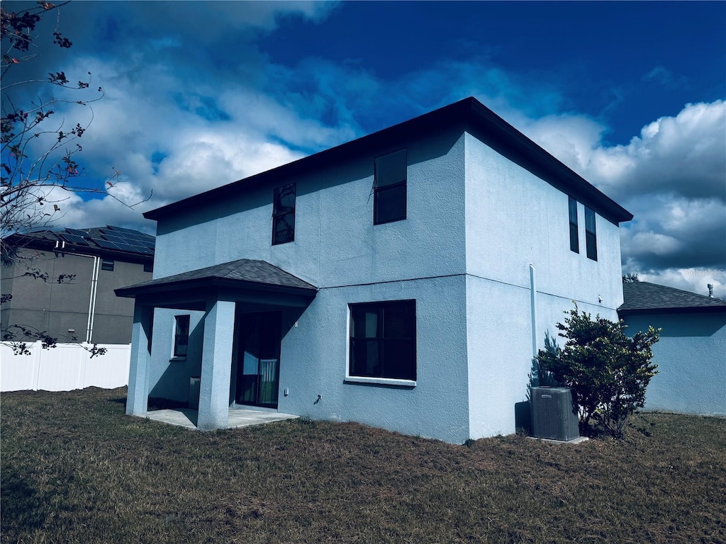 back of property featuring central AC unit and a yard