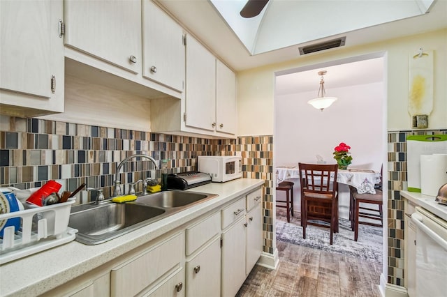 kitchen with sink, a skylight, hardwood / wood-style flooring, tasteful backsplash, and decorative light fixtures