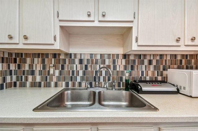 kitchen with backsplash, light stone countertops, and sink