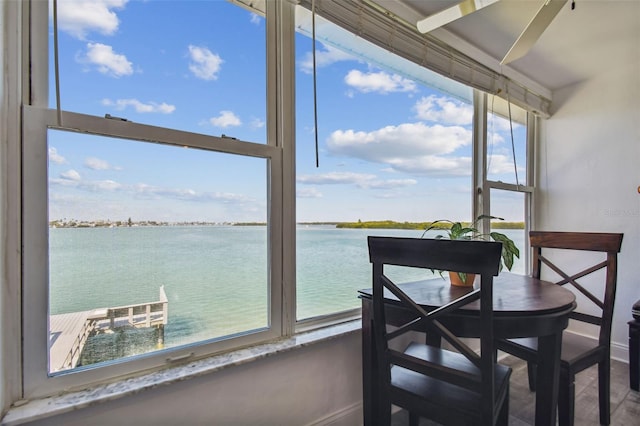 sunroom / solarium with plenty of natural light, ceiling fan, and a water view