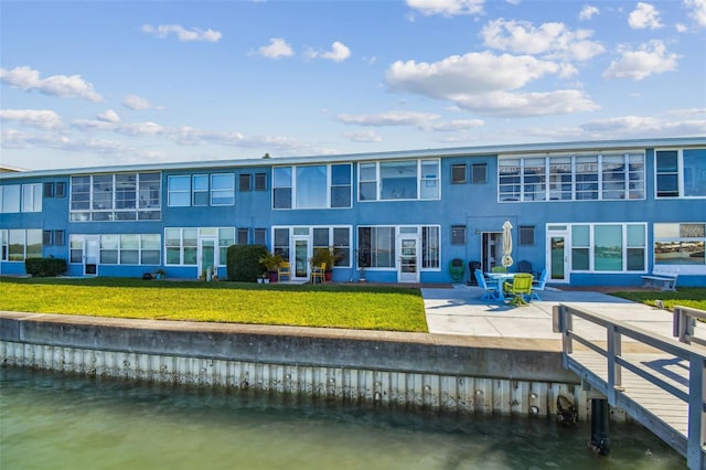 rear view of property with a lawn, a water view, and a patio