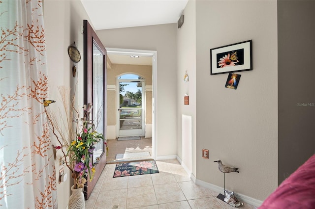 entrance foyer with light tile patterned floors and vaulted ceiling