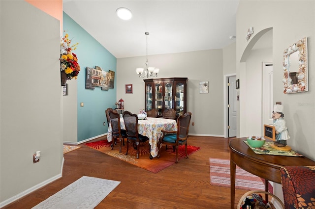 dining area with wood-type flooring, lofted ceiling, and a notable chandelier